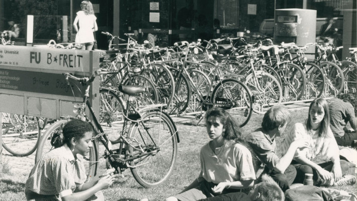  Studierende sitzen vor Gebäude der FU